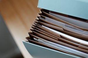 High Angle Of Opened Briefcase For Documents With Papers Accosted In Order Placed On Wooden Table